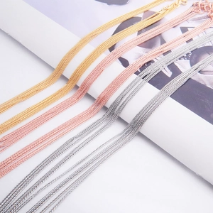Detailed view of layered link chains in gold, rose gold, and silver finishes