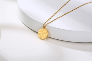 Detailed view of the gold stainless steel necklace featuring a round Fu pendant charm