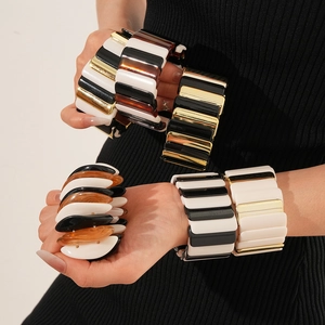 Detail of multi-color resin and gold metal elastic bangle bracelets on model wrist