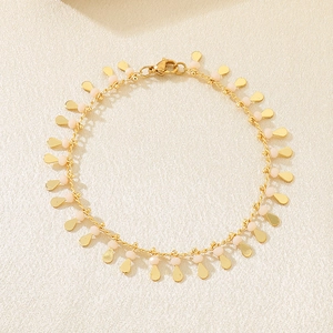Detailed close-up of golden teardrop charms and pink beads on a stylish bracelet