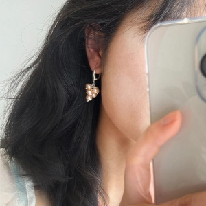 Close-up of elegant grape cluster pearl earrings worn on ear with silver hoop design