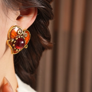 Close-up of vintage heart earrings with red resin and gold edges on model