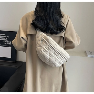 Close-up of beige quilted crossbody chest bag worn on model's back over a stylish trench coat