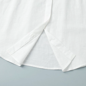 Close-up of white linen shirt dress with curved hem and textured fabric detail