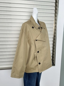 Detail of khaki short trench coat with double-breasted buttons and twill cotton texture