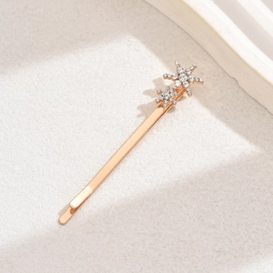 Close-up of golden alloy hair clip featuring two sparkling rhinestone-studded stars