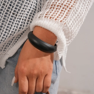 Close-up of a minimalist black chunky acrylic open cuff bracelet on a model wrist
