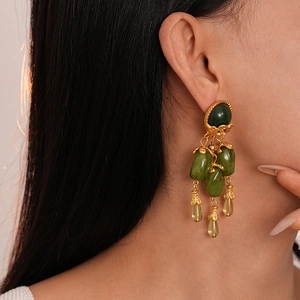 Gros plan de boucles d'oreilles vintage en résine vert olive sur un mannequin doré