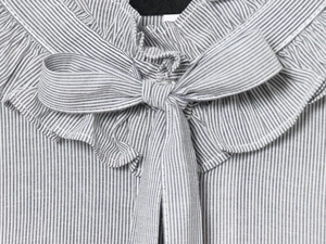 Detail of the ruffled neckline with striped fabric and a delicate bow tie on a blouse
