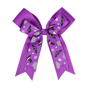 Detail of purple Halloween hair bow featuring spider webs and witch hat prints on ribbon