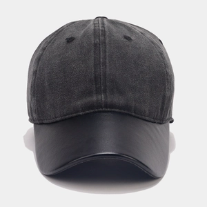 Detail of dark grey baseball cap featuring a black leather brim and contrast fabric texture