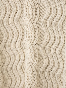 Macro shot of Fair Isle knit sweater showing detailed cable stitch patterns in cream white