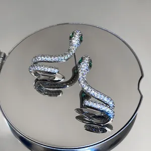 Détail macro de boucles d'oreilles serpent en argent avec zircons et yeux verts