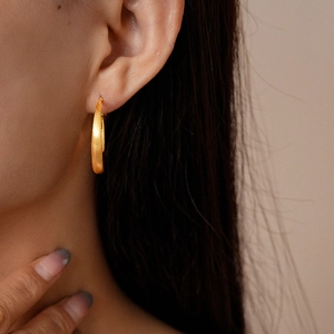 Close-up of matte 18k gold plated hoop earring on model showing brushed metal texture