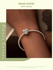 Wrist-worn silver chain bracelet with heart-shaped green gemstone and vintage details