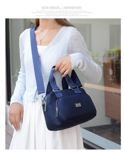 Close-up of a large-capacity navy nylon handbag with front zipper pocket and silver logo