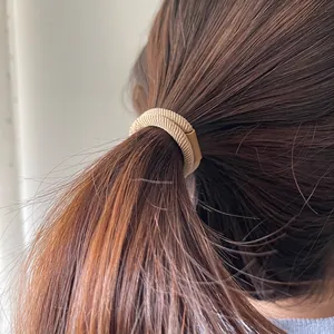 Neutral brown woven elastic hair tie with rectangular accent on a low ponytail