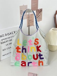 Detail of canvas tote bag featuring colorful 'Let's think about earth' embroidery