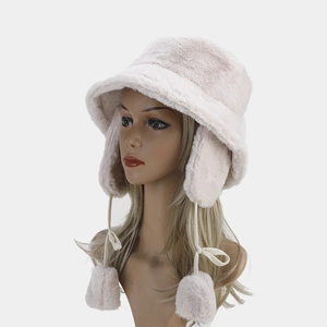 Detail of plush faux fur texture and pom-pom ties on winter thermal earflap bucket hat