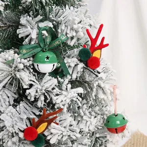 Christmas tree bell ornaments and reindeer antler hair clips on snowy branch decor