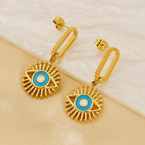Exotic golden evil eye drop earrings with blue enamel detailing on a silk background