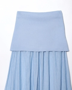 Détail du haut en tricot bleu ciel cousu avec un tissu de jupe plissé texturé