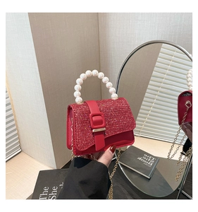 Detailed shot of red glitter mini handbag featuring pearl handle and gold chain strap