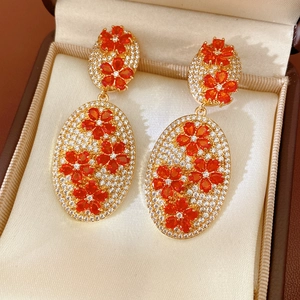 Detail of vintage oval drop earrings with orange zircon stones and gold finish