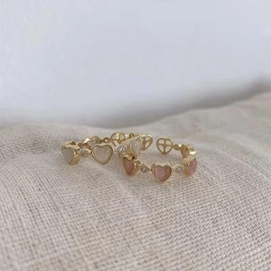 Macro detail of gold-plated rings featuring pink and white opal heart gemstones