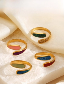 Dettaglio di anelli geometrici placcati in oro con smalto multicolore su fondo in seta