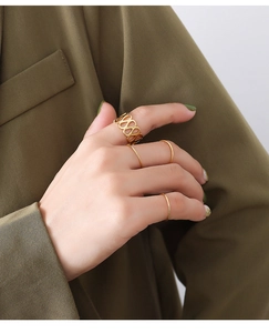 Detail of minimalist gold-plated rings including a hollow geometric band on a model