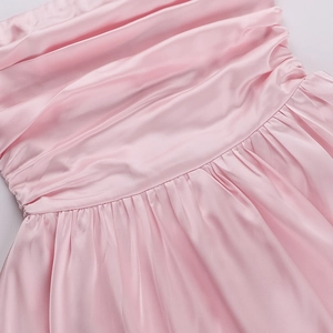 Close-up of pink satin dress fabric showing refined pleats and silky texture