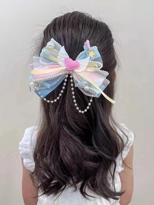 Detail of macaron bow hair clip with lace edging, pink heart, and pearl chain tassels