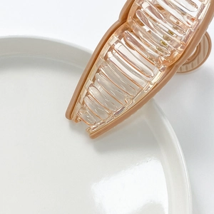 Brown and transparent large striped hair claw clip on a white ceramic plate