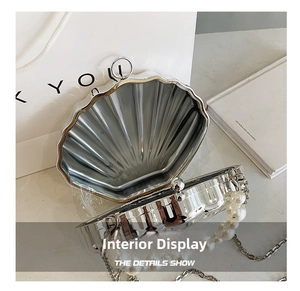 Detail view of silver shell-shaped evening bag with pearl chain and metal texture