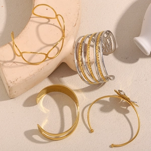 Detail view of four 18K gold plated stainless steel bangles with floral and geometric designs