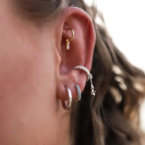 Close-up of gold and silver hoop earrings with white zircon on ear model