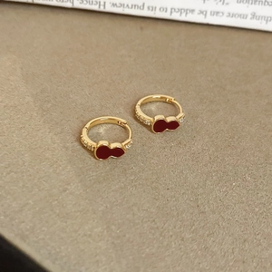 Detailed macro view of gold-plated gourd earrings with red enamel and zircon accents