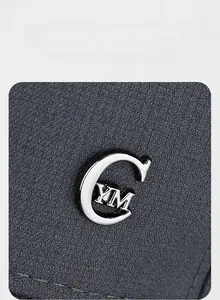 Dettaglio del logo metallico C argento lucido su berretto da baseball grigio scuro