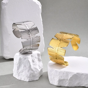 Detail of leaf-shaped open bangles in gold and silver finish on decorative white stone