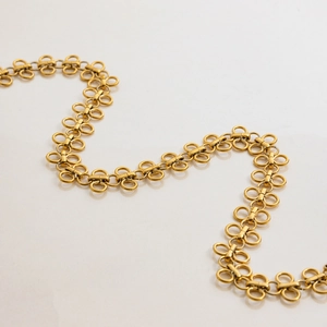 Elegant gold titanium clover necklace with unique alternating link chain on white surface