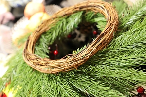 Detailed view of Christmas wreath featuring green pine needles, red berries, and natural brown vine