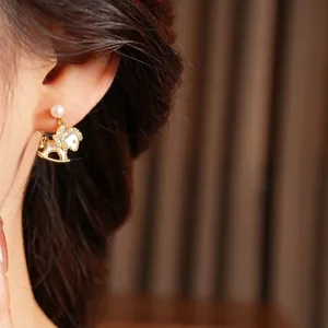 Elegant 14k gold plated pearl earrings with zircon rocking horse charms on model