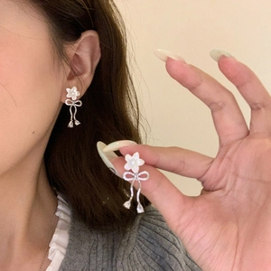Detail of flower bow earrings with pearls and crystals worn on a model ear