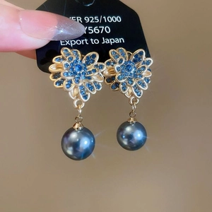 Dettaglio di orecchini a fiore in argento vintage con zirconi blu e perle grigie