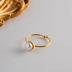 Detail of adjustable gold ring with a single white freshwater pearl in minimalist style