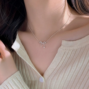 Silver bow knot necklace with sparkling rhinestones worn by a model in soft lighting