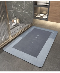 Modern blue non-slip bathroom mat with HOME lettering on a gray marble floor