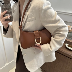 Deep brown matte leather crescent underarm bag with gold horseshoe buckle on model