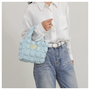Close-up of light blue pleated handbag with golden bow detail and quilted texture